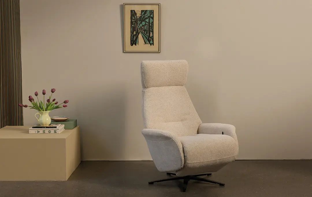 Heller Sessel vor beiger Wand, links Beistelltisch mit Tulpen und Bild an der Wand
